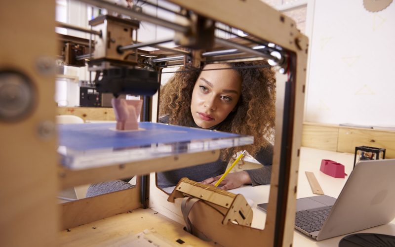 Female Designer Working With 3D Printer In Design Studio